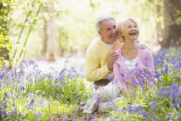 Couple assis à l'extérieur avec des fleurs souriantes — Photo