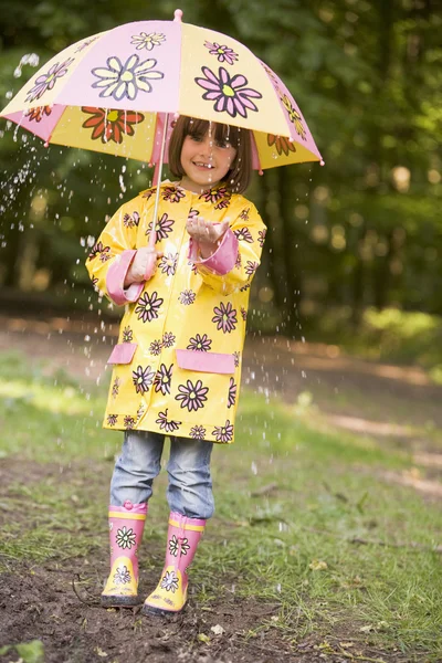 Νεαρή κοπέλα σε εξωτερικούς χώρους στη βροχή με ομπρέλα χαμογελώντας — Φωτογραφία Αρχείου