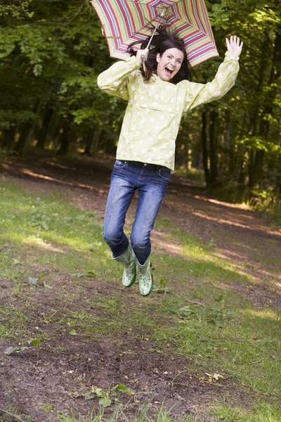 Woman outdoors jumping with umbrella smiling — Stock Photo, Image