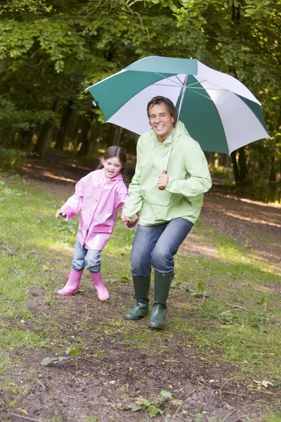 Father and daughter outdoors with umbrella smiling — Stock Photo, Image