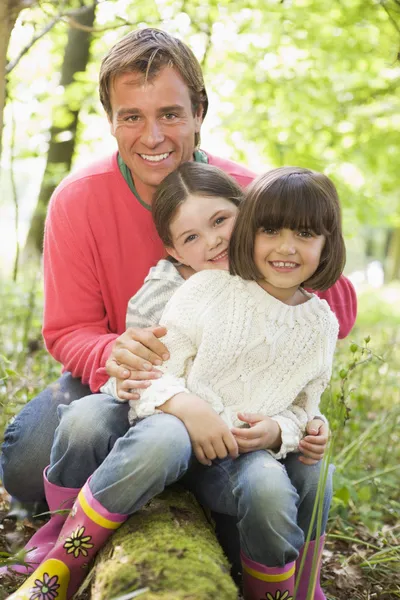 父亲和女儿在树林里有关日志微笑坐在户外 — 图库照片