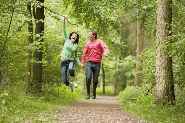 Couple Jumping Path Holding Hands Smiling — Stock Photo, Image