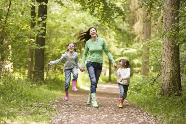 Madre e figlie che saltano sul sentiero sorridendo — Foto Stock