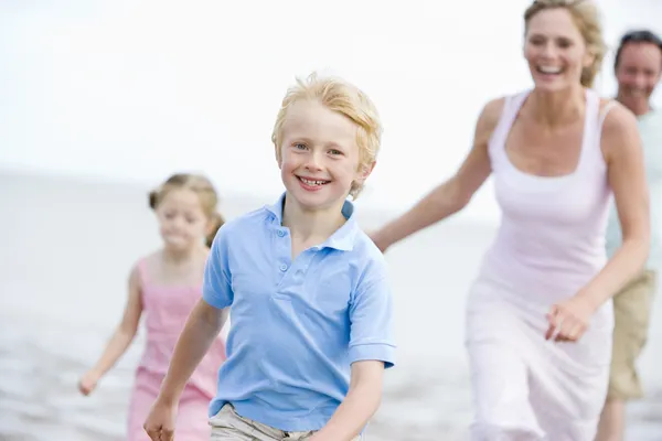 Família correndo na praia sorrindo — Fotografia de Stock