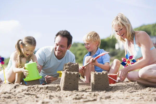 Rodzina na plaży co uśmiechający się zamki z piasku — Zdjęcie stockowe