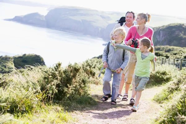Family walking on cliffside path pointing and smiling — Stock Photo, Image