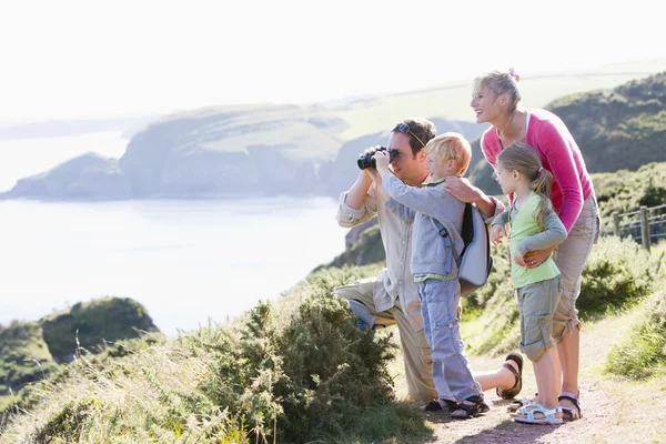 Family on cliffside path using binoculars and smiling — Stock Photo, Image