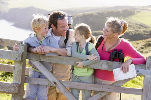 Familie op cliffside pad leunend op hek en glimlachen — Stockfoto