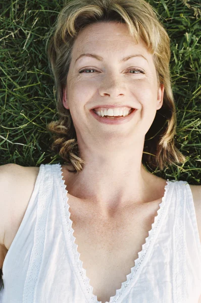 Mulher deitada ao ar livre sorrindo — Fotografia de Stock