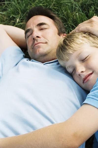 Father and son lying outdoors sleeping — Stock Photo, Image
