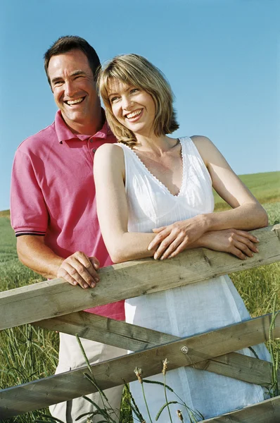 Paar staande buiten door het hek glimlachende — Stockfoto