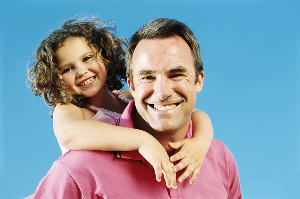 Pai dando filha piggyback passeio ao ar livre sorrindo — Fotografia de Stock