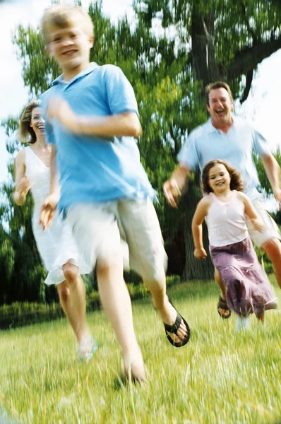 Familie läuft lächelnd ins Freie — Stockfoto