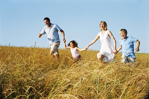 Familia corriendo al aire libre tomados de la mano sonriendo — Foto de Stock
