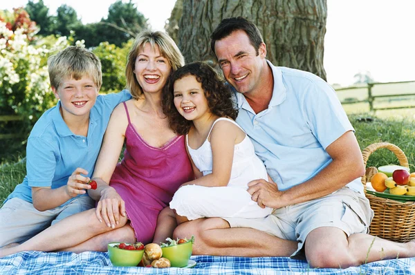 Familjen sitter utomhus med picknick leende — Stockfoto