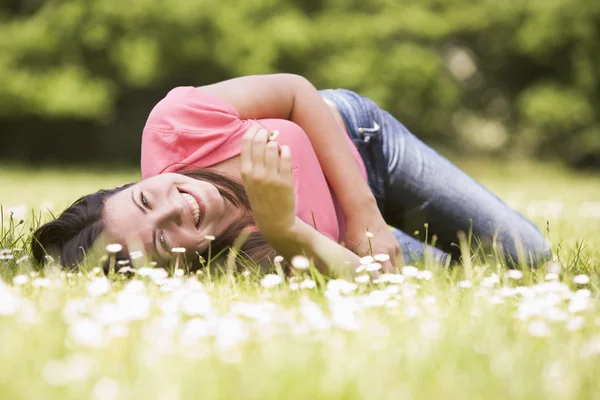 Mulher deitada ao ar livre com flor sorrindo — Fotografia de Stock