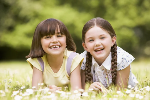 Two sisters lying outdoors smiling — Stock Photo, Image