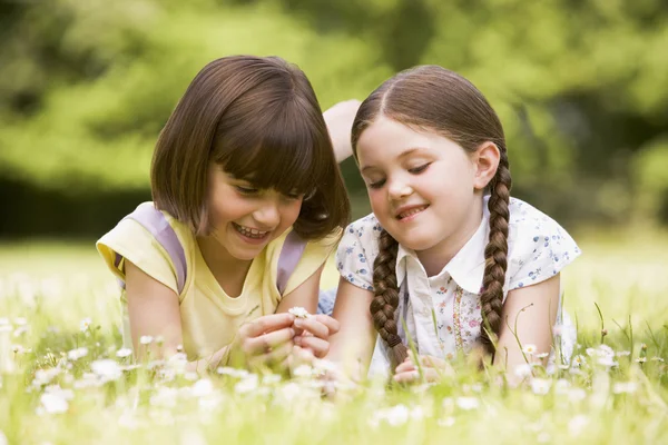 Twee zusters buiten liggen met bloem glimlachen — Stockfoto