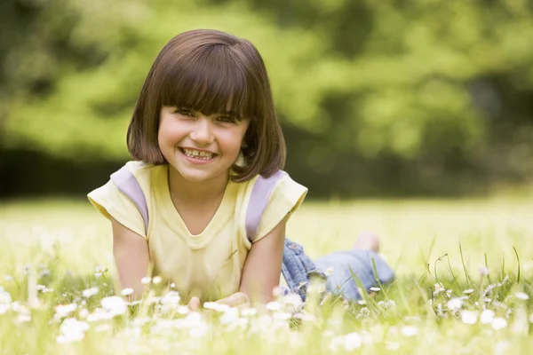 Young girl lying outdoors smiling — Stock Photo, Image