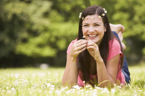 Woman lying outdoors with flowers smiling — Stockfoto