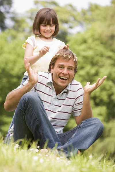 父亲和女儿坐在户外微笑的花朵 — 图库照片