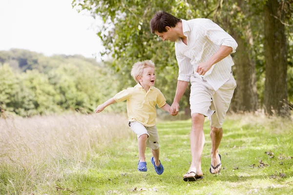 Father and son running on path holding hands smiling — Stock Photo, Image