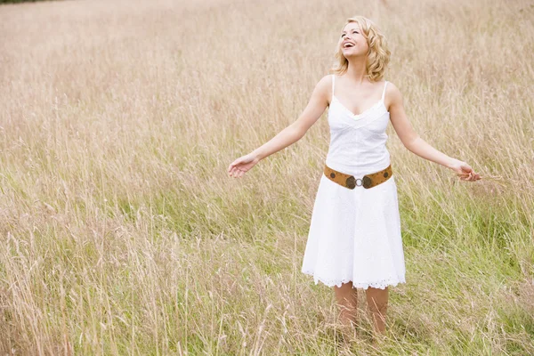 Woman standing outdoors holding grass smiling — Stock Photo, Image