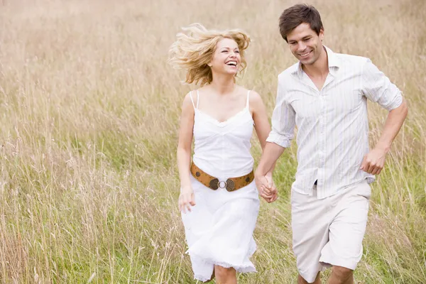 Casal correndo ao ar livre de mãos dadas sorrindo — Fotografia de Stock
