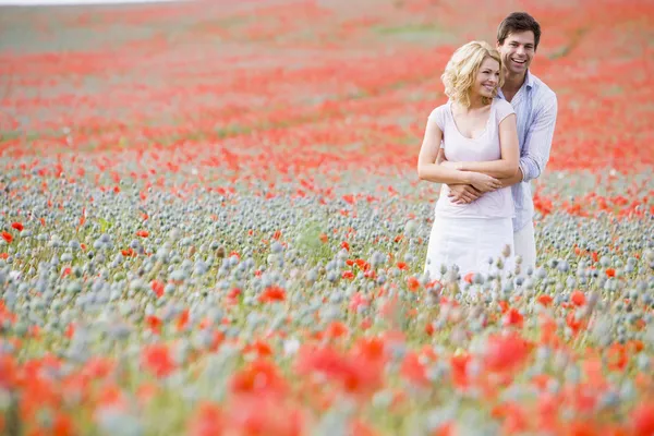 Couple in poppy field embracing and smiling — Stock Photo, Image