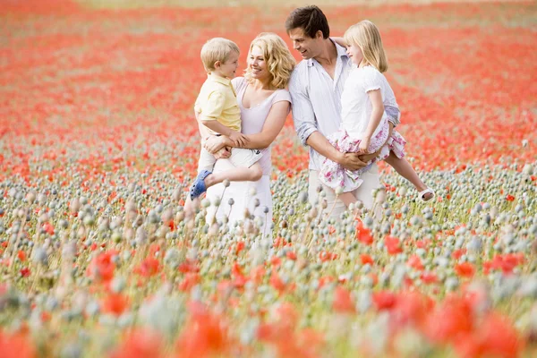 Семья, стоящая на маковом поле улыбаясь — стоковое фото