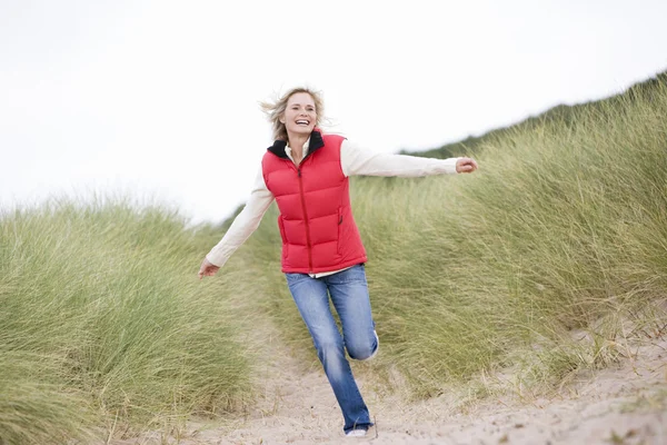 Жінка біжить на пляжі посміхається — стокове фото