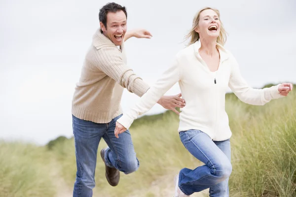 Casal correndo na praia sorrindo — Fotografia de Stock