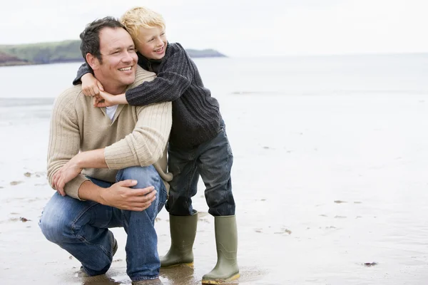 Отец и сын на пляже улыбаются — стоковое фото
