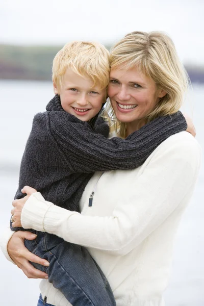 Mãe segurando filho na praia sorrindo — Fotografia de Stock