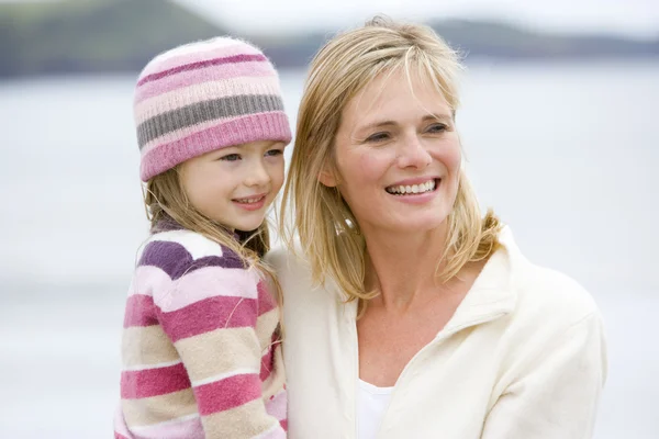 Mutter hält Tochter lächelnd am Strand — Stockfoto