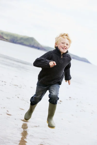 Menino correndo na praia sorrindo — Fotografia de Stock