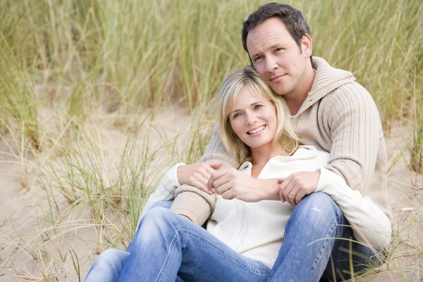 Пара сидящих на пляже улыбающихся — стоковое фото