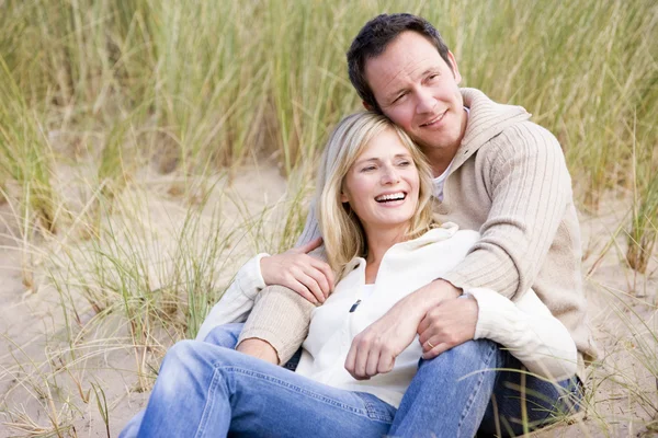 Casal sentado na praia sorrindo — Fotografia de Stock