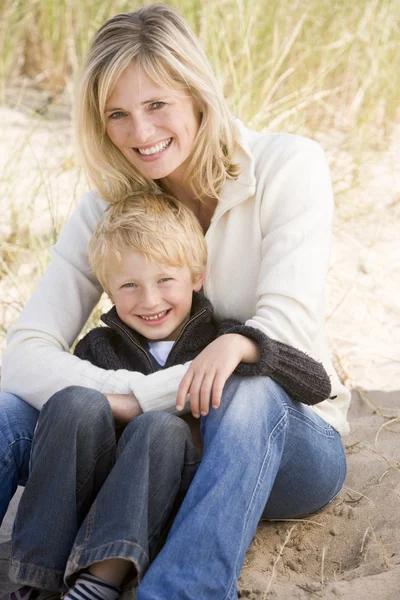 Мать и сын сидят на пляже улыбаясь — стоковое фото