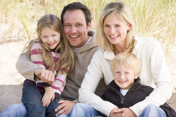 Familjen sitter på stranden leende — Stockfoto