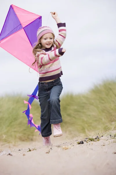 Young girl on beach with kite smiling — Stock Photo, Image