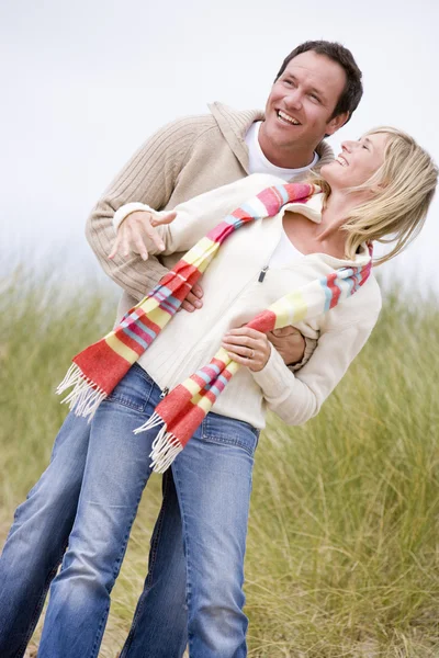 Par som står på stranden leende — Stockfoto