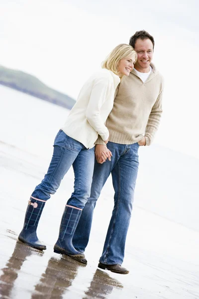 Пара прогулок по пляжу держась за руки улыбаясь — стоковое фото