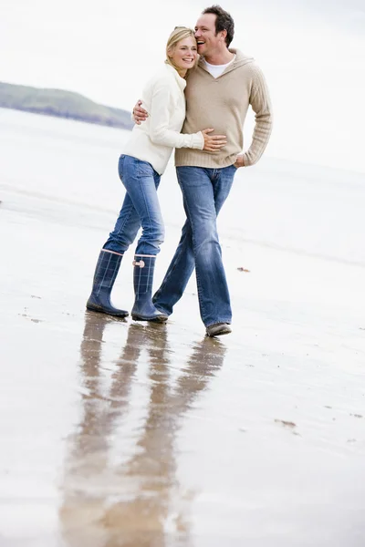 Pár chůze po pláži ruku v paži s úsměvem — Stock fotografie