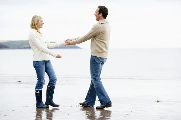 Couple marchant sur la plage se tenant les mains souriantes — Photo