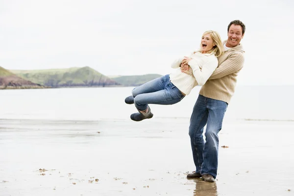 Par som spelar på stranden leende — Stockfoto