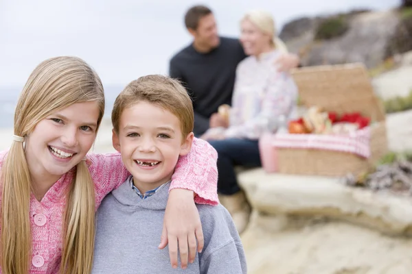 Familia en la playa con picnic sonriendo — Foto de Stock