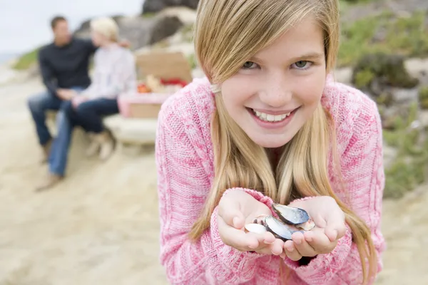 Famiglia in spiaggia con pic-nic sorridente attenzione sulla ragazza con conchiglie — Foto Stock