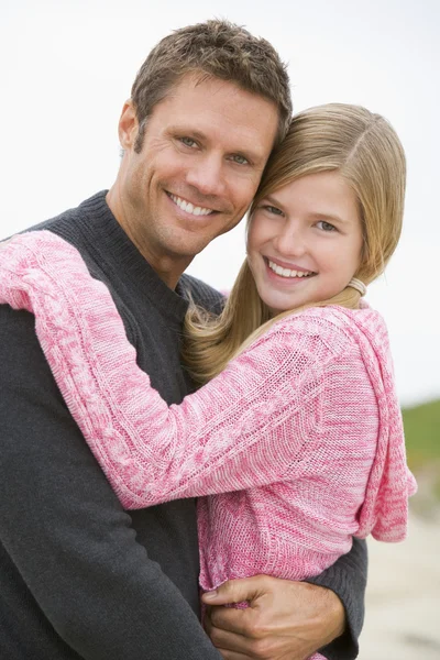 Отец держит дочь на пляже улыбаясь — стоковое фото