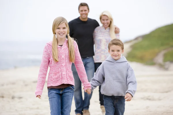 Familia caminando en la playa tomados de la mano sonriendo — Foto de Stock